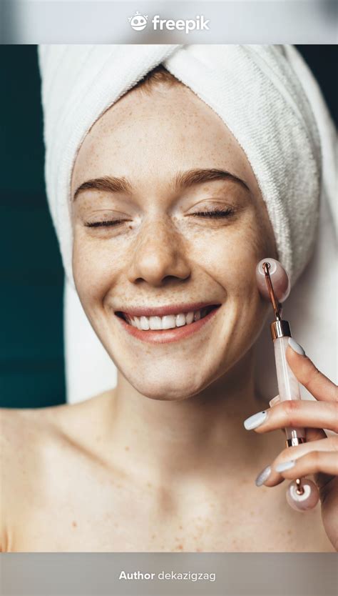 Freckled Woman Is Using A Facial Massage Roller Smiling While Covering Head With Towel And