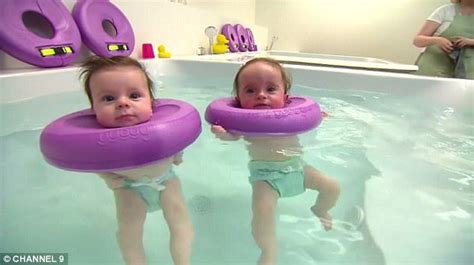 Two Babies Are Playing In The Water With Large Purple Swimming Floats