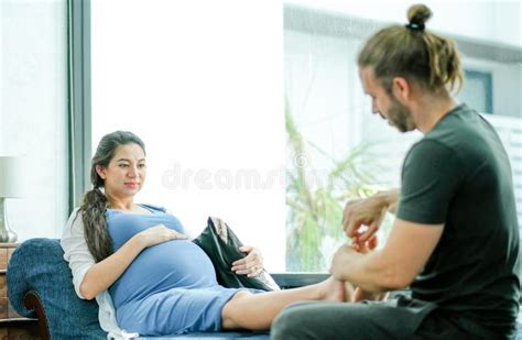 Man Massage To Foot And Leg Of His Pregnant Wife Who Sit On Sofa In