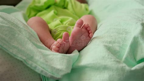 Newborn Baby Wearing Green Bodysuit Lying On Back At Home Tiny Baby