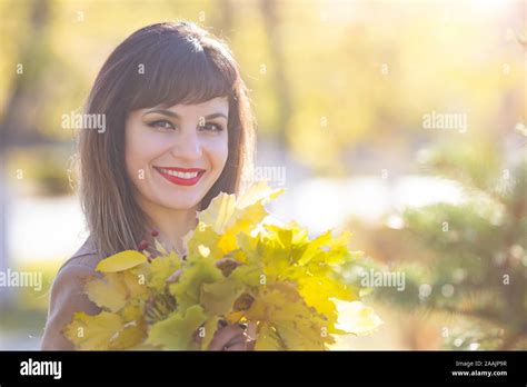 pretty woman 25 30 years old with black hair a luxurious smile with yellow autumn leaves in her