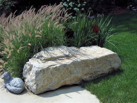 A Large Rock Sitting On Top Of A Grass Covered Ground Next To A Garden