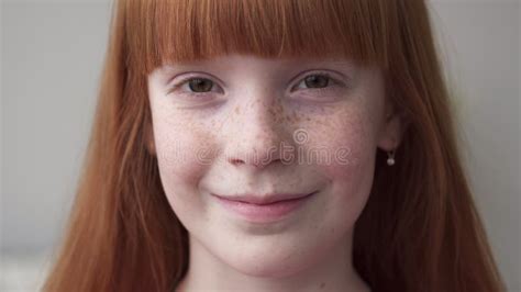 Happy Ginger Teenage Girl With Freckles Smiling Against White Wall
