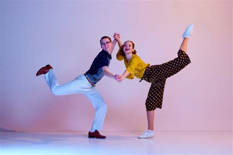 Happy Emotional Young Couple Man And Woman In Stylish Clothes Dancing Retro Dance Against