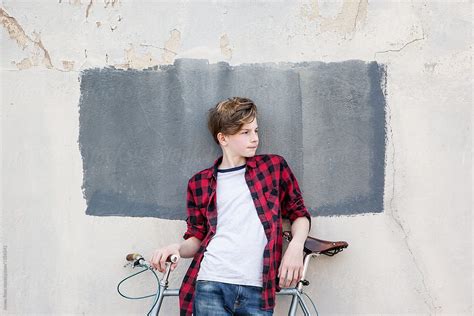 Male Teenager Waiting By A Wall With Bicycle By Stocksy Contributor
