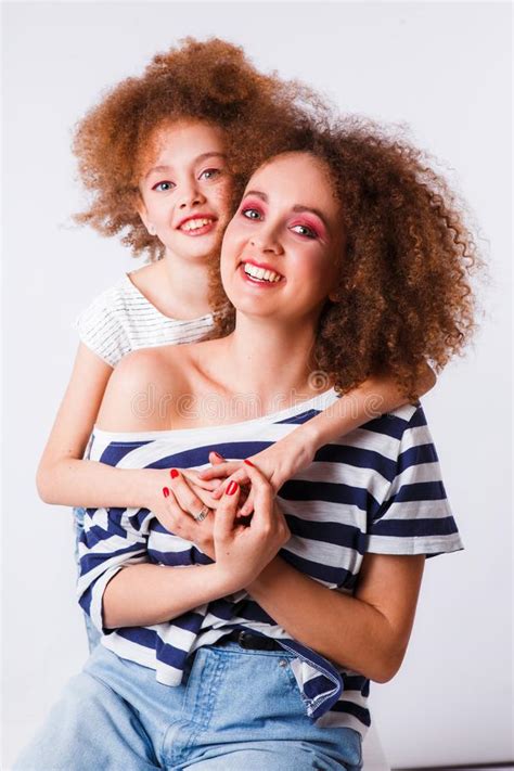 Mom And Daughter With Natural Small Curls On The Head On A Light