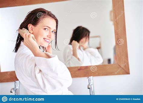 Photo Of Brunette Woman Combing Her Hair In Front Of Bathroom Mirror
