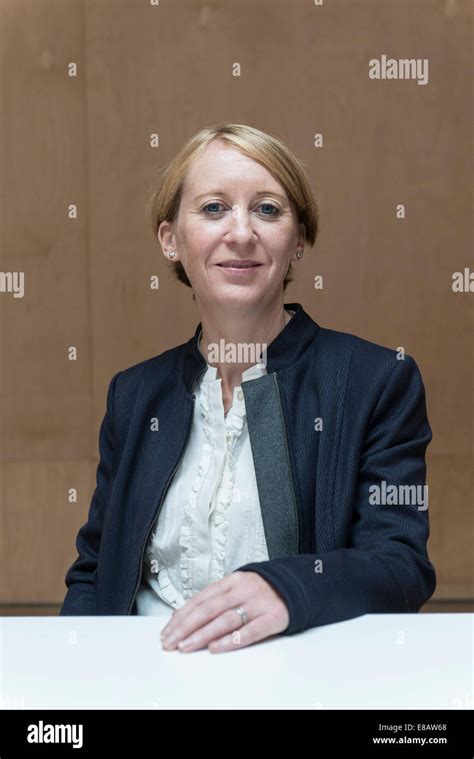 Short Haired Business Woman Sits At A Table In A Meeting Room Wearing A Business Suit Looking