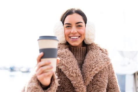 Premium Photo Young Woman Wearing Winter Muffs And Holding Take Away