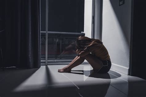 deprimida mujer joven sentada sola en el suelo de la sala de estar foto premium