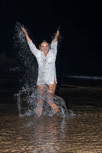 beautiful model girl making splashes in the sea and laughing at night beautiful woman enjoying