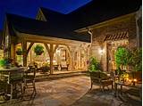 Traditionally styled brick patio showcases a stone fire pit and is surrounded by beautiful raised beds and stone plant holders. Patio Ideas | HGTV