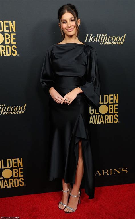 A Woman Standing On Top Of A Red Carpet Wearing A Black Dress And High