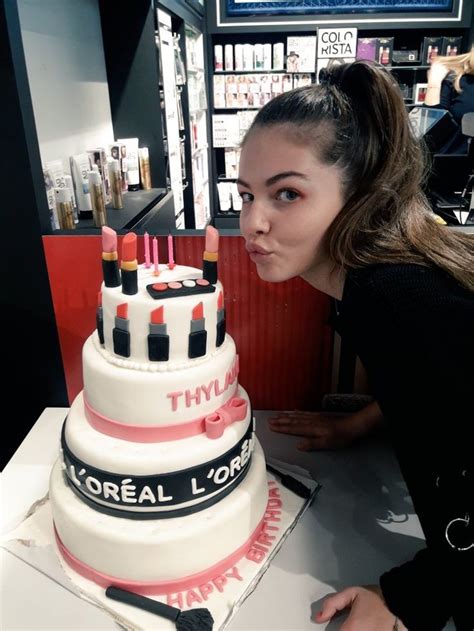 A Woman Blowing Out Candles On Top Of A Cake That Is Decorated With Lipstick And The Words L