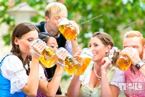 Four Friends Drinking Beer At The Same Time In Bavarian Beer Garden