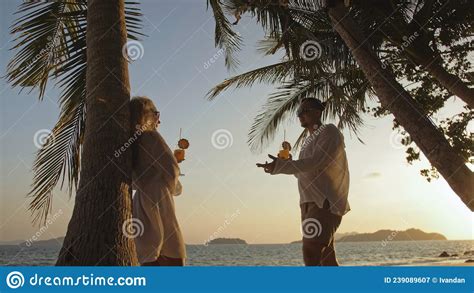 The Man Goes To The Woman Loving Couple Near Palm Tree Kissing Stock