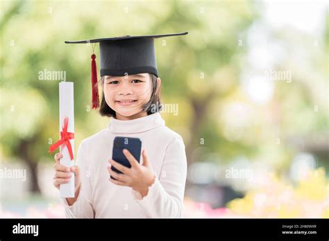 Happy Southeast Asian Schoolgirl With A Certificate And Smartphone During Graduation In Thailand
