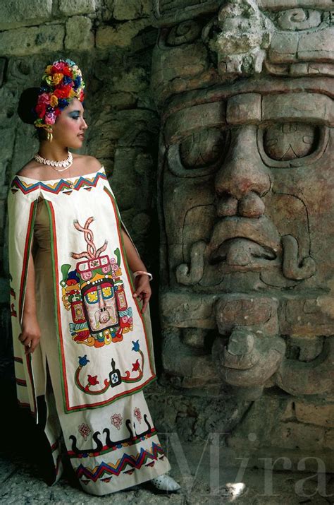 Young Woman In Mayan Dress Posing By Statue Of Sun God At Mayan Ruins