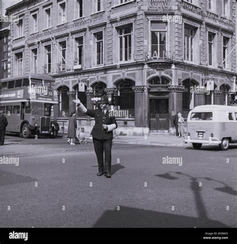 1960 historical daytime and a uniformed british policeman with hemet is seen directing traffic