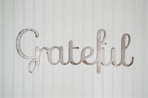 A Metal Sign That Says Grateful Hanging On The Wall Next To A White