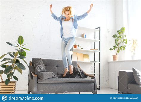 funny woman jumping on black couch in living room stock image image of caucasian cheerful