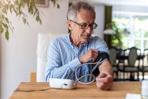 Senior Man Using Medical Device To Measure Blood Pressure Heart