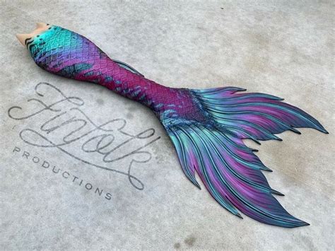 A Purple And Blue Mermaid Tail Laying On Top Of A Cement Floor Next To