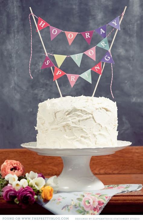 A White Cake Sitting On Top Of A Table Next To Flowers And A Chalkboard