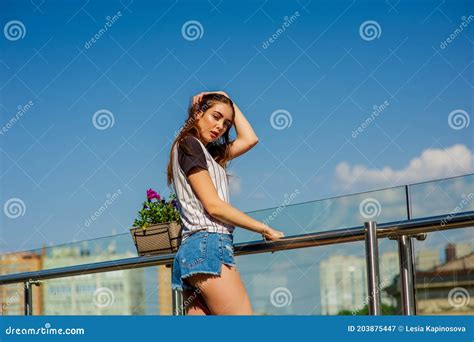 Girl In Denim Shorts On The Balcony Mini Denim Shorts Woman In A Striped Shirt Stock Image