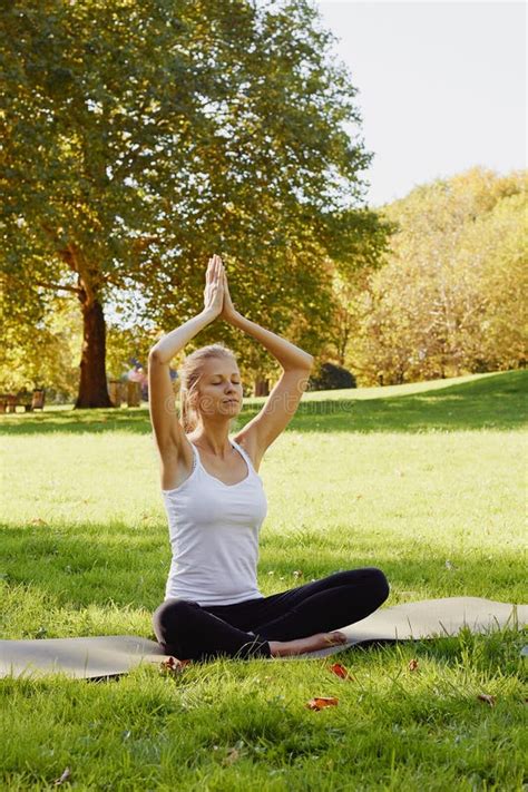 Girl Meditates While Practicing Yoga Outdoors In Park Stock Photo