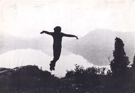 A Black And White Photo Of A Person Jumping In The Air With Their Arms Outstretched
