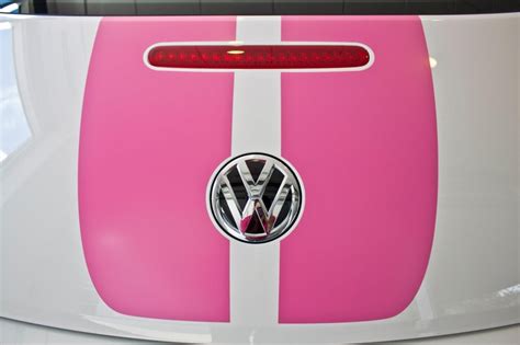 the vw emblem is on the hood of a white and pink car