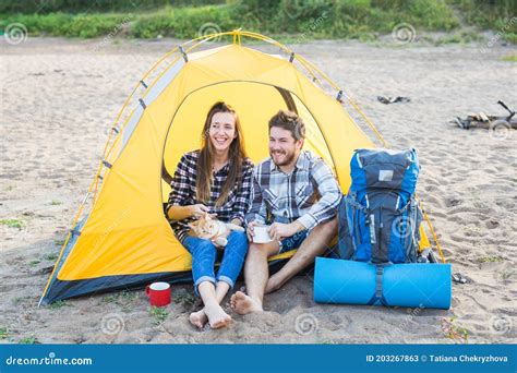 People Tourism And Nature Concept Cute Couple Sitting With A Cat In Yellow Tent Stock Image