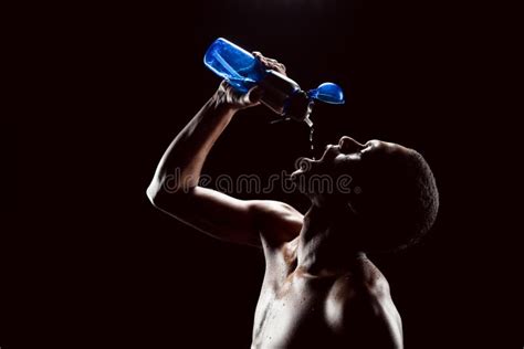 Sporty African Man Drinking Water After Training On Black Stock Image