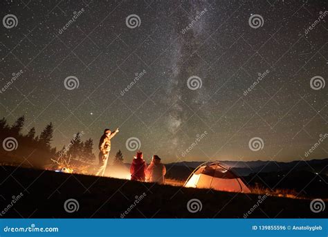 Friends Resting Beside Camp Campfire Under Night Starry Sky Stock