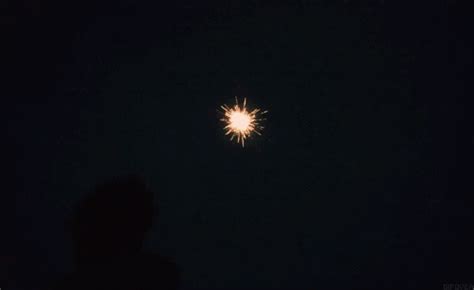 A Person Standing In The Dark Looking At A Fireworks