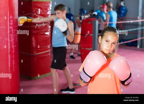 Portrait Of Glad Girl Boxer Wearing Rose Gloves In Boxing Hall Stock