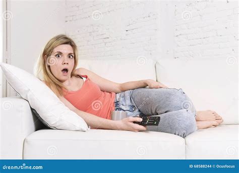 Young Woman On Sofa Holding Television Remote Controller Watching Tv