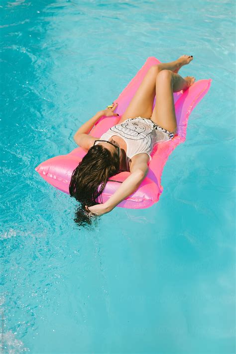 Brunette Woman Relaxing On The Floating Bed In The Swimming Pool By Stocksy Contributor