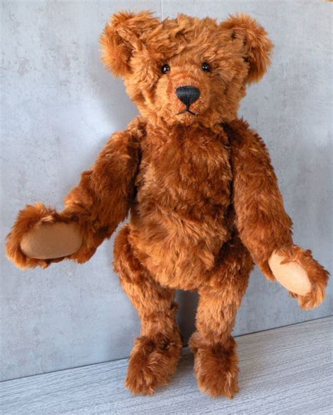 A Brown Teddy Bear Standing Up Against A Wall