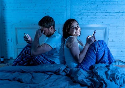 Frustrated Man And Addicted Woman Couple Using Mobile Phones In Bed At Night Ignoring Each Other