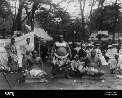 Three Sumo Wrestlers Posed Outdoors With Spectators In Background