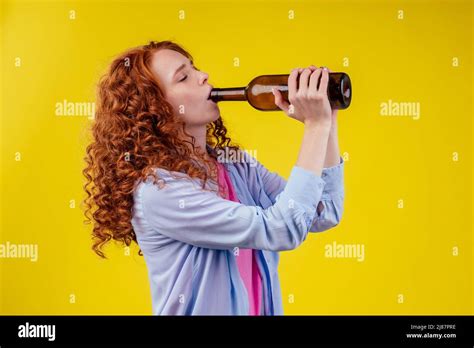 Curly Redhead Ginger Woman Drinking Beer And Feeling Bad Mood In Csudio Yellow Background Stock