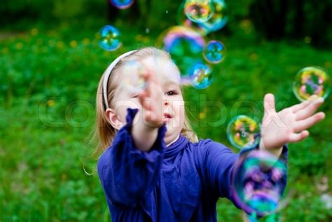 Little Girl In Park Catching Bubbles Stock Image Colourbox