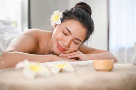 Beautiful Calm Asian Woman Lying On Massage Table With Eyes Closed In Beauty Spa Salon Stock