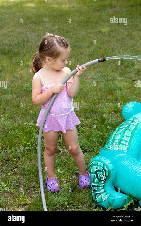 4 Year Old Girl Filling An Inflatable Pool With Water Stock Photo Alamy