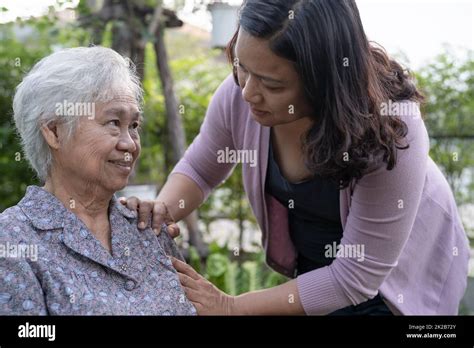 caregiver daughter help asian senior or elderly old lady woman on electric wheelchair in park
