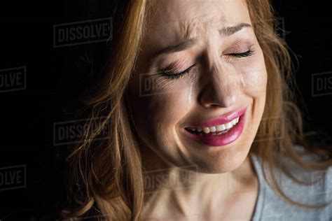 Close-up portrait of young beautiful woman crying isolated on black ...