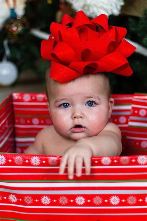 A Baby With A Red Bow On Her Head In A Christmas T Box By A