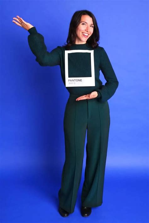 A Woman Wearing Green Pants And A Black Sweater Is Holding Her Arms Out In The Air